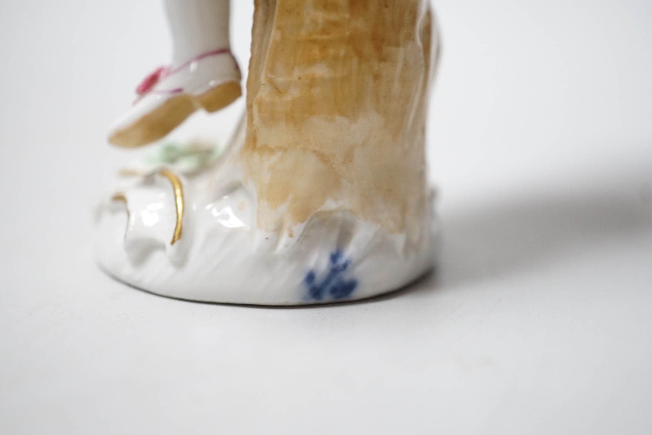 A Meissen figure of a young man with walking stick and his tail full of flowers, late 18th century, blue crossed swords to back of base